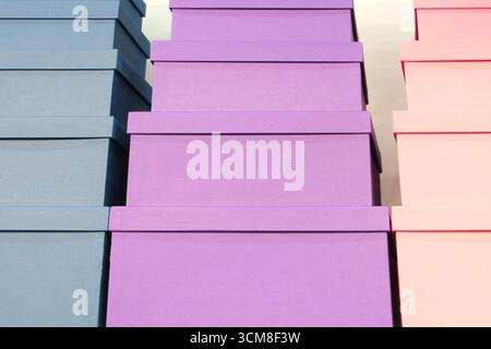 Stapel von Schachteln mit lila und rosa Schachteln übereinander. Die Felder haben unterschiedliche Farben und Größen. Stockfoto
