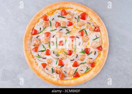 Hühnchen-Pizza mit Pilzen, Kirschtomaten und grünen Zwiebeln auf Käsebasis Stockfoto