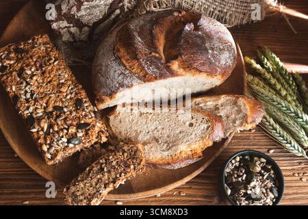 Gesundes hausgemachtes Brot mit Weizenohren dekoriert. Frisch geschnittenes Brot auf einem Holzbrett. Stockfoto