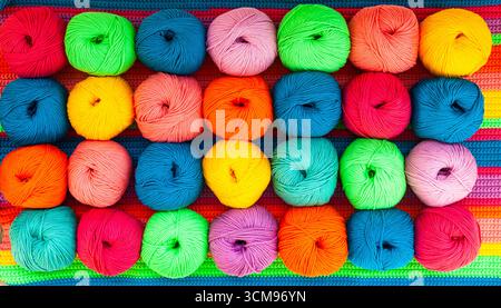 Many multi-colored balls of threads on a knitted fabric, close-up. Stockfoto