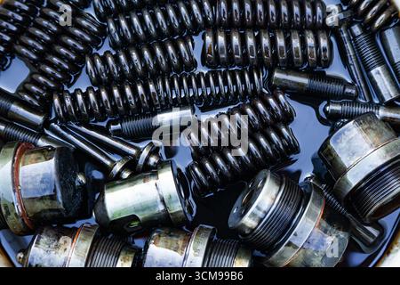 Mechanische Stahlteile mit Maschinenöl geschmiert, Nahaufnahme. Stahleinspritzdüsen, Federn, Buchsen, Bolzen und Gewindeteile in Öl. Stockfoto