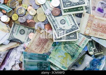 Geld aus verschiedenen Ländern der Welt ist in einem Stapel von Münzen und Banknoten verstreut. Amerikanische Dollar, rumänischer lei, serbische Dinar, Euro und HR Stockfoto