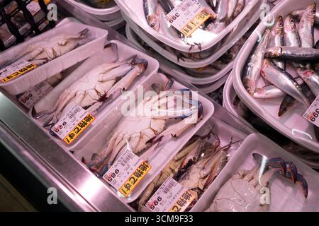 Krabben und Sardinen werden in Styroporbehältern verpackt und im Meeresfrüchte-Bereich eines Lebensmittelgeschäfts in Japan verkauft. Stockfoto