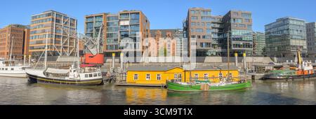 Farbenfrohe Boote und historische Lagerhäuser stehen im ruhigen Wasser des Hamburger Hafens nebeneinander. Stockfoto