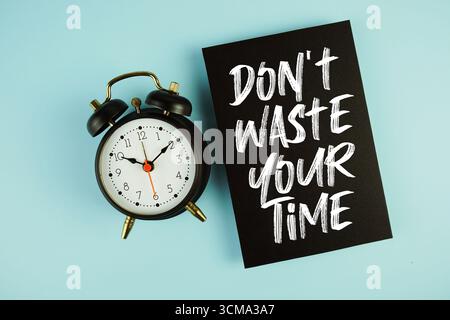 Verschwenden Sie Ihren TimeUp to Date-Text nicht mit einem Wecker auf blauem Hintergrund Stockfoto