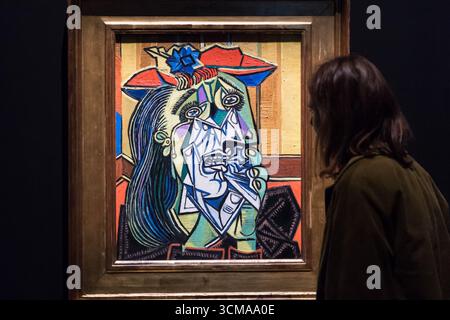 London, Großbritannien. September 2025. LONDON, VEREINIGTES KÖNIGREICH - 15. SEPTEMBER 2025: Ein Galeriemitarbeiter sieht sich „Weeping Woman“, 1937, von Pablo Picasso während eines Fotoaufrufs für die Ausstellung „Theatre Picasso“ (17. September 2025 - 12. April 2026) in der Tate Modern in London, Vereinigtes Königreich am 15. September 2025 an. Die Ausstellung zeigt einige der bekanntesten Werke Picassos aus Tates Sammlung sowie wichtige Darlehen führender Picasso-Museen in Frankreich, die in einem Theater-inspirierten Set inszeniert werden. (Foto: Wiktor Szymanowicz/NurPhoto) Credit: NurPhoto SRL/Alamy Live News Stockfoto