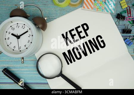 Halten Sie beweglichen Text auf Notizblock mit Wecker und Lupe flach auf hölzernem Hintergrund Stockfoto