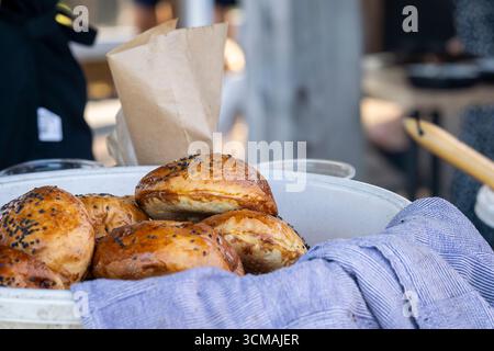 Hamburger Brötchen mit schwarzen Sesamsamen. Runde Sandwichbrötchen mit schwarzem Sesam. Hausgemachtes Brötchen für Burger in Schüssel. Stockfoto