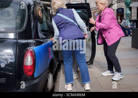 Frauen, die die Hauptstadt besuchen, bekamen am 15. September 2025 ein schwarzes Taxi in der City of London, dem Finanzviertel der Hauptstadt, in London, England. Stockfoto