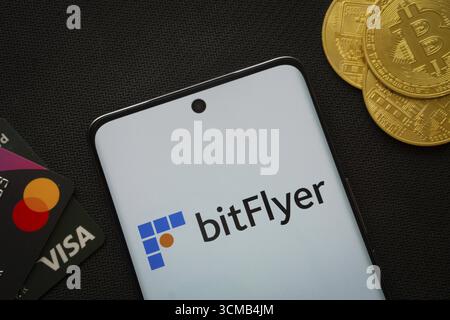Dhaka, Bangladesch, 02. Juni 2025: Smartphone mit Bitflyer-Logo, umgeben von Bitcoin-Münzen und Zahlungskarten Stockfoto