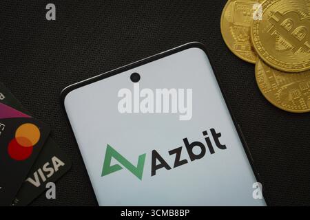 Dhaka, Bangladesch, 02. Juni 2025: Smartphone mit Azbit-Logo, umgeben von Bitcoin-Münzen und Zahlungskarten Stockfoto