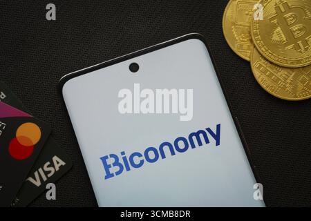 Dhaka, Bangladesch, 02. Juni 2025: Smartphone mit Biconomy-Logo, umgeben von Bitcoin-Münzen und Zahlungskarten Stockfoto