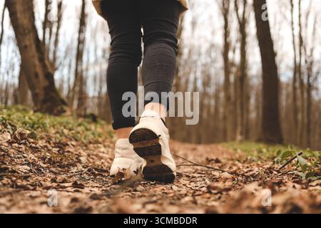 Nahaufnahme einer Frau, die im Wald läuft. Sportschuhe. Bäume und Blätter im Hintergrund. Aktives und gesundes Lifestyle-Konzept. Stockfoto