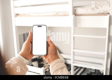 Telefon mit isoliertem Bildschirm im Kinderzimmer vor dem Hintergrund eines Stockbetts, Möbel bestellen. Stockfoto