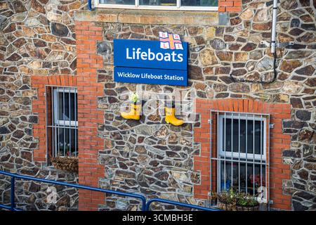 Nahaufnahme der Fassade der Wicklow Lifeboat Station mit RNLI-Schild, Emblem und gelben Stiefeln, Wicklow, irische Küste. Stockfoto