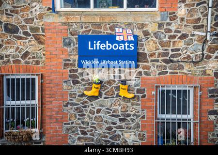 Nahaufnahme der Fassade der Wicklow Lifeboat Station mit RNLI-Schild, Emblem und gelben Stiefeln, Wicklow, irische Küste. Stockfoto