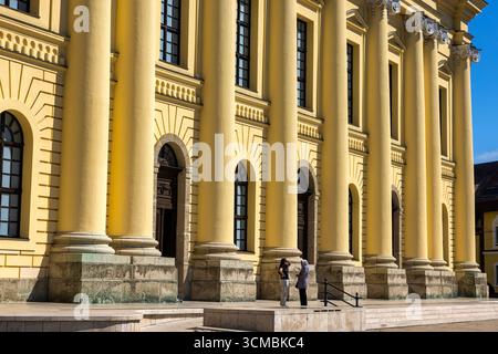 Debrecen, Ungarn 30. Juli 2025 – neoklassizistisches Gebäude mit gelben Säulen, Bogenfenstern, Steinfuß und Sonnenlicht, das dramatische architektonische Elemente hervorbringt Stockfoto
