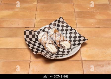 Pistazien-Cannoli mit einer natürlich grün getönten Schale, gefüllt mit Pistazien und Ricotta-Creme, garniert mit gehackten Pistazien und essbarer Goldfolie Stockfoto