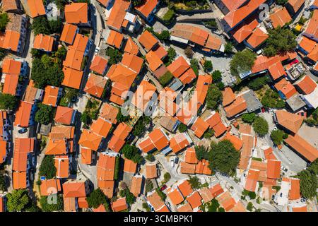 Blick aus der Vogelperspektive auf Chora mit rot gekachelten Dächern, engen Gassen und üppigem Grün in einem historischen Bergdorf. Stockfoto