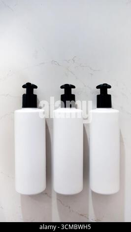 Realistisches Modell, drei leere Etiketten Weiße Flaschen oder Behälter, Schwarzer Pumpkopf Tropfer an weißer Marmorwand, Toilettenartikel, Shampoo, Duschgel, Condi Stockfoto