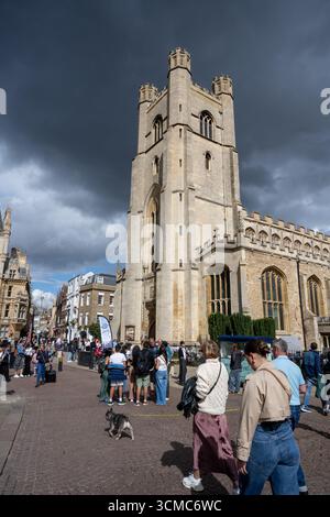 Great St Mary’s Church, Cambridge, historische Universitätskirche mit Menschenmassen und dramatischen Sturmwolken über den belebten Straßen der Stadt Stockfoto