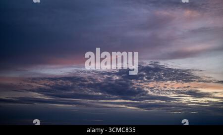 Farbenfroher Sonnenuntergang mit dramatischen Wolken über dem Horizont. Ein atemberaubender Abendhimmel mit warmem Licht. Stockfoto