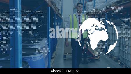 Ein Mann in einer Sicherheitsweste, der den Gang des Lagers hinunterzieht, mit blauen Trommeln und einer Weltkarte Stockfoto