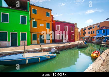 Helle, farbenfrohe Häuser, die den Kanal mit vertäuten Booten säumen, auf der Insel Burano in der Nähe von Venedig, Veneteo, Italien. Stockfoto