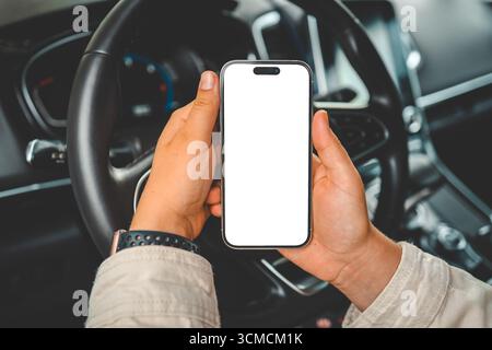 Ein Telefon mit einem isolierten Bildschirm in den Händen einer Frau in einem Auto. Stockfoto