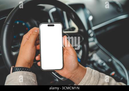 Ein Telefon mit einem isolierten Bildschirm in den Händen einer Frau in einem Auto. Stockfoto