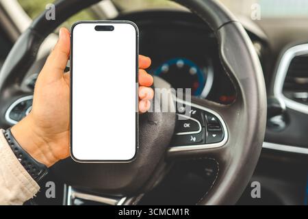 Ein Telefon mit einem isolierten Bildschirm in den Händen einer Frau in einem Auto. Stockfoto
