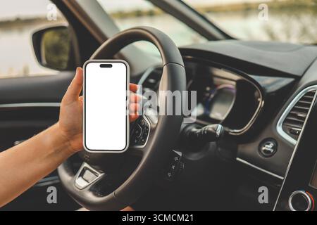 Ein Telefon mit einem isolierten Bildschirm in den Händen einer Frau in einem Auto. Stockfoto