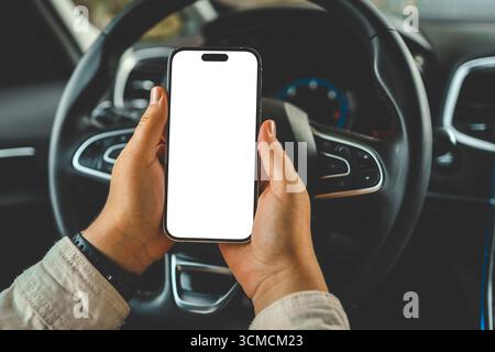 Ein Telefon mit einem isolierten Bildschirm in den Händen einer Frau in einem Auto. Stockfoto