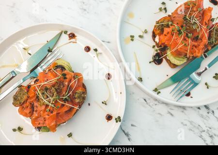 Gesundes Frühstück. Avocadotoast mit Lachs und pochierten Eiern auf Keramikplatte. Stockfoto