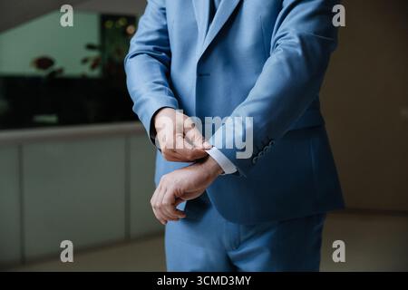 Mann verstellbare Ärmel aus blauem Anzug, Nahaufnahme, eleganter formeller Stil, drinnen Stockfoto