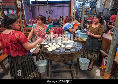 Chichicastenango, Guatemala - 3. Juli 2025: Frauen machen Tortillas auf dem Santo Tomas Markt in Chichicastenango, Guatemala. Stockfoto