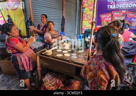 Chichicastenango, Guatemala - 3. Juli 2025: Frauen machen Tortillas auf dem Santo Tomas Markt in Chichicastenango, Guatemala. Stockfoto
