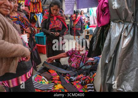 Chichicastenango, Guatemala - 3. Juli 2025: Frauen kaufen traditionelle Kleidung auf dem Santo Tomas Markt in Chichicastenango, Guatemala. Stockfoto