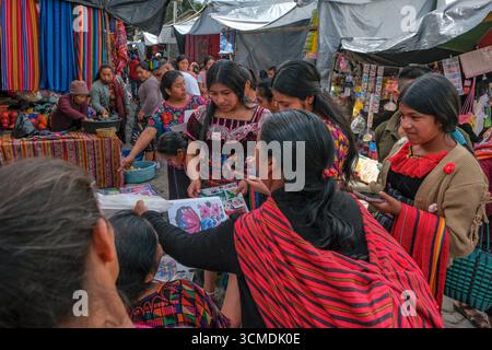 Chichicastenango, Guatemala - 3. Juli 2025: Frauen kaufen Stickmuster auf dem Santo Tomas Markt in Chichicastenango, Guatemala. Stockfoto