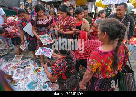 Chichicastenango, Guatemala - 3. Juli 2025: Frauen kaufen Stickmuster auf dem Santo Tomas Markt in Chichicastenango, Guatemala. Stockfoto