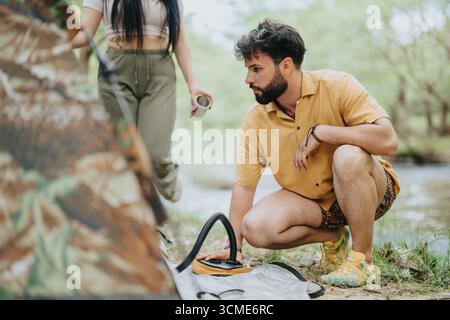 Freunde, die ein Camp in der Nähe eines beruhigenden Flusses in einem ruhigen Wald gründen Stockfoto
