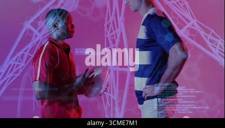 Im pinken Studio stehen zwei Athleten im Rugby-Ball mit Wireframe-Hexagon-Code-Overlays gegenüber Stockfoto