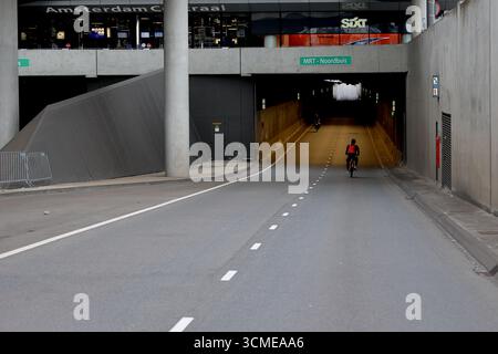 Radfahrer betreten die MRT Noordbuis unter de Ruijterkade von Amsterdam Centraal während Sail 2025, Amsterdam, Niederlande, aus dem Straßeneinstieg. Stockfoto