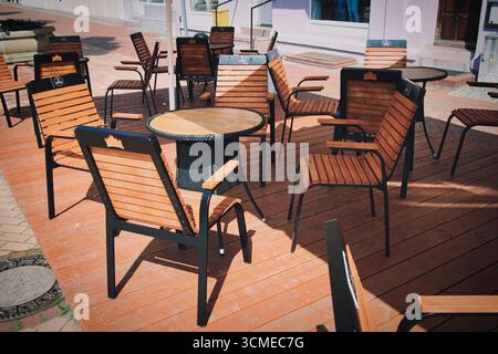 Eine Holzterrasse mit einem Tisch und Stühlen. Die Stühle sind kreisförmig um den Tisch angeordnet Stockfoto