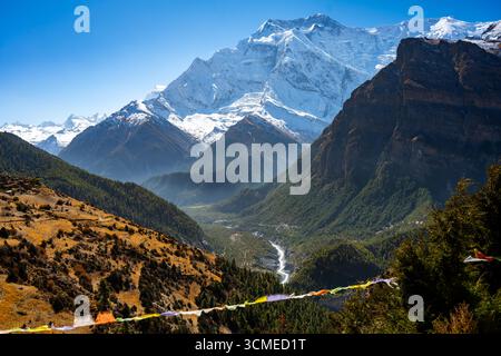 Panoramablick auf das Annapurna-Massiv von Ghyaru, Nepal mit Gebetsflaggen und Deep Valley Stockfoto