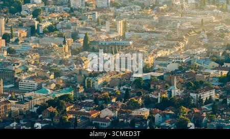 Blick auf die Altstadt von Sarajevo mit der Kathedrale des Heiligen Herzens, Moscheen und traditionellen Dächern im goldenen Abendlicht Stockfoto