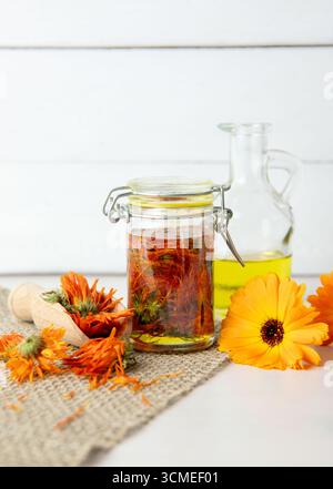 Herstellung von hausgemachtem Calendula officinalis gewöhnlichem Ringelblumenkaltinfusionsöl im Glasgefäß. Trockene Blüten werden bei Raumtemperatur in Olivenöl eingeweicht. Stockfoto