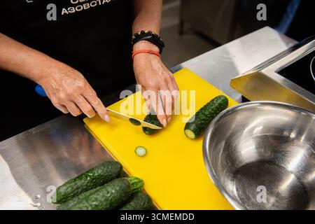 Weibliche Hände schneiden eine Gurke Stockfoto