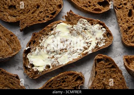 Handwerklich geschnittenes Roggensauerteigbrot mit Butterblick von oben. Kulinarische Hintergründe Stockfoto