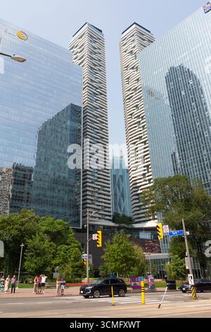Downtown Toronto Street Szene mit Wolkenkratzern, die wie Riesen über den Menschen auf dem Bürgersteig thronen. Reflektionen anderer Gebäude in den Glasfenstern. Stockfoto